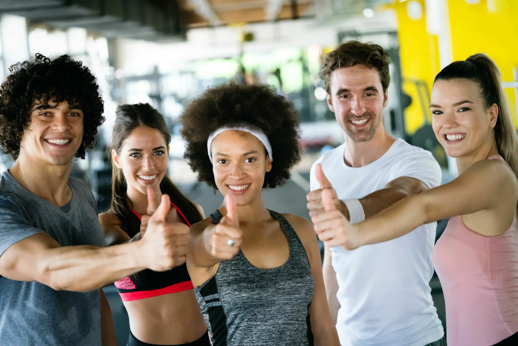 Group of happy multiracial friends exercising together in gym